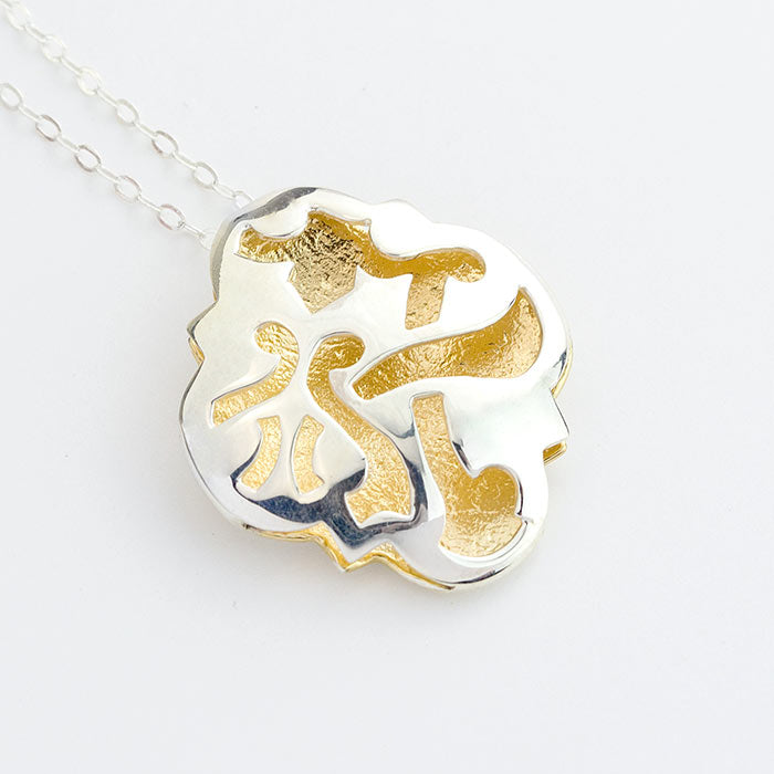 Fretwork quatrefoil pendant in silver and gold.