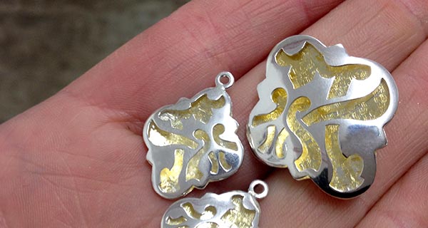 Handmade quatrefoil fretwork pendant and earring panels in sterling silver and 23ct gold gilding.